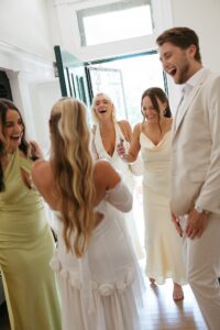 Brides celebrating their summer wedding at Wild Carrot in St. Louis with bridesmaids in pale yellow and chartreuse dresses and bridesmen in beige suits.