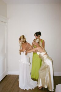 Brides celebrating their summer wedding at Wild Carrot in St. Louis with bridesmaids in pale yellow and chartreuse dresses and bridesmen in beige suits.
