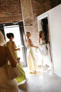Modern LGBTQ wedding at Wild Carrot in St. Louis featuring pale yellow and chartreuse bridesmaid dresses, simple calla lily bouquets, and a brick reception space.