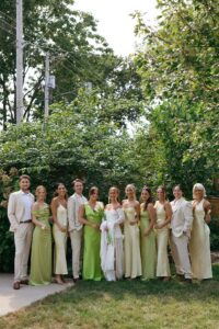 Brides celebrating their summer wedding at Wild Carrot in St. Louis with bridesmaids in pale yellow and chartreuse dresses and bridesmen in beige suits.