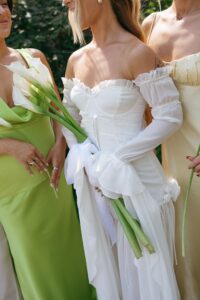 Brides celebrating their summer wedding at Wild Carrot in St. Louis with bridesmaids in pale yellow and chartreuse dresses and bridesmen in beige suits.