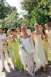 Brides celebrating their summer wedding at Wild Carrot in St. Louis with bridesmaids in pale yellow and chartreuse dresses and bridesmen in beige suits.