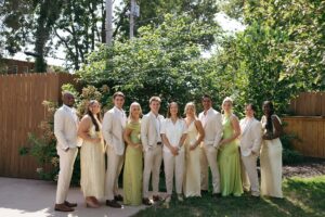 Brides celebrating their summer wedding at Wild Carrot in St. Louis with bridesmaids in pale yellow and chartreuse dresses and bridesmen in beige suits.