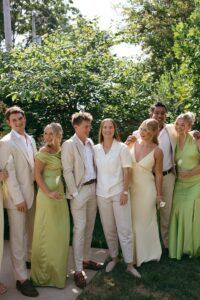 Brides celebrating their summer wedding at Wild Carrot in St. Louis with bridesmaids in pale yellow and chartreuse dresses and bridesmen in beige suits.