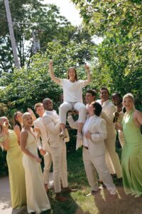 Brides celebrating their summer wedding at Wild Carrot in St. Louis with bridesmaids in pale yellow and chartreuse dresses and bridesmen in beige suits.