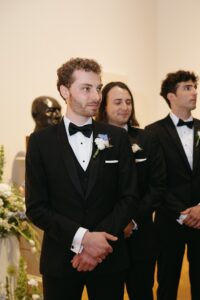 Intimate indoor ceremony during a rainy day St. Louis Art Museum wedding with pastel florals and pale blue bridesmaid dresses.