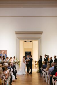Intimate indoor ceremony during a rainy day St. Louis Art Museum wedding with pastel florals and pale blue bridesmaid dresses.