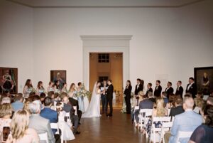 Intimate indoor ceremony during a rainy day St. Louis Art Museum wedding with pastel florals and pale blue bridesmaid dresses.