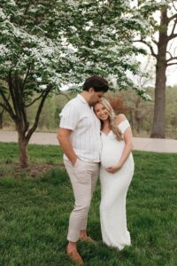 maternity portraits of Jen wearing a fitted white dress in a spring field at Queeny Park St. Louis