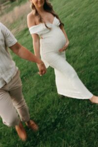 maternity portraits of Jen wearing a fitted white dress in a spring field at Queeny Park St. Louis