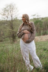 maternity photos of Jen wearing white linen pants and beige cardigan with bump visible at Queeny Park